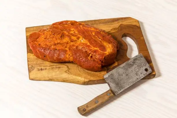 Meat, Pork neck in marinade and on a chopping boardon. Raw steak meat pork neck on chopping board with chili. Raw meat for grilling. White background.