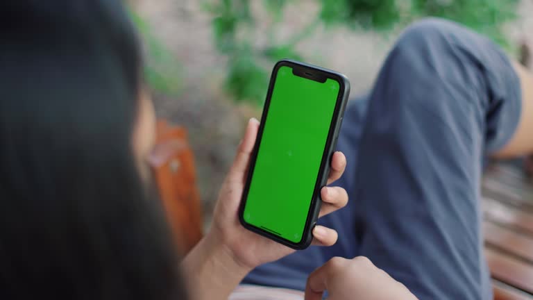 Young woman uses smartphone with green screen