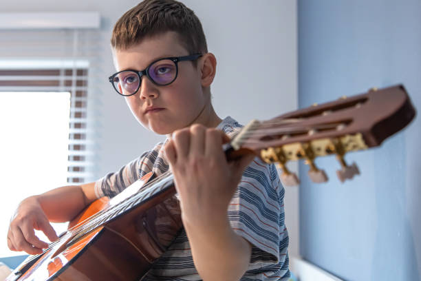istock Little boy plays the classical guitar at home, on the bed. 1318572476
