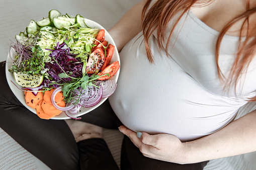 The expectant mother in the last months of pregnancy eats a salad of fresh vegetables.