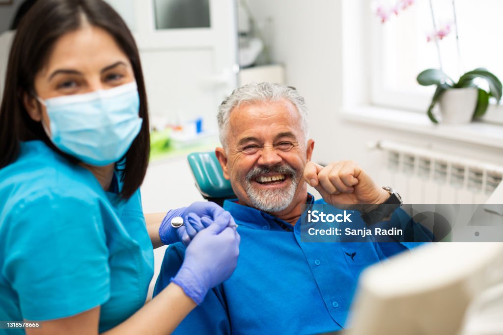 Joking with my dentist An elderly man likes to go to his dentist because he is relaxed there, having no fears, making jokes, and laughing with her. Dental Health Stock Photo