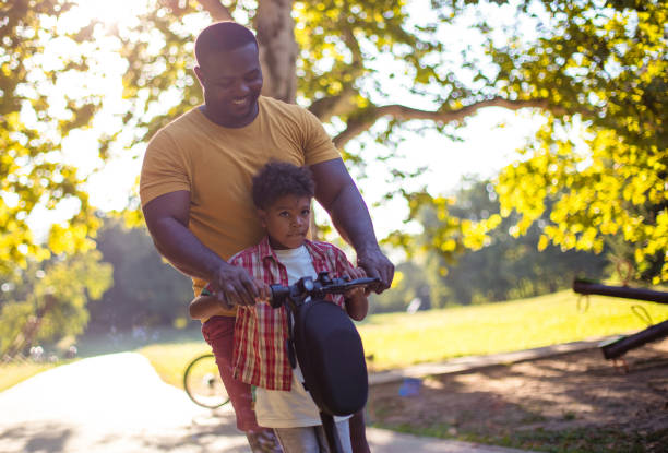 istock African American father having fun outdoors with his son. Ride on push scooter. 1318579672