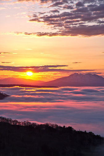 A dramatic dawn with a sea of ​​clouds under the shining morning sun. Bihoro Pass in Hokkaido, Japan.