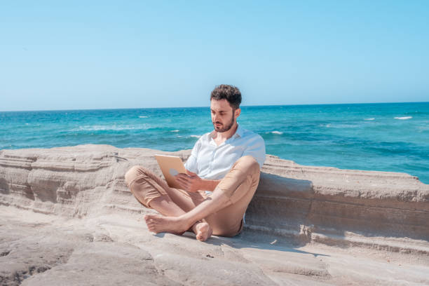 jeune homme d’affaires ayant la conversation web vidéo en ligne avec la tablette numérique sur la plage - reading beach e reader men photos et images de collection