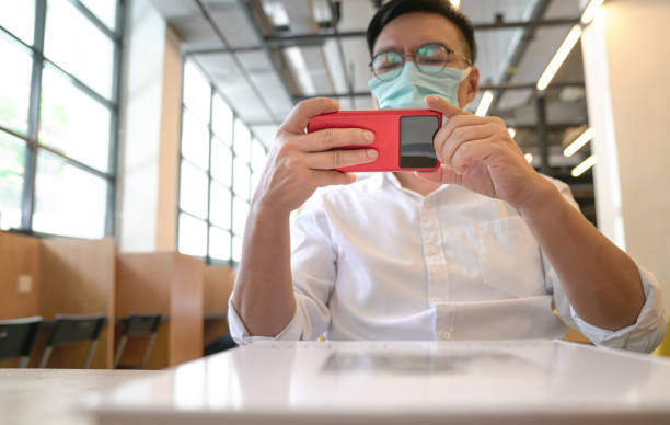 istock Man wearing face mask using his phone to watch or take video. 1318582464