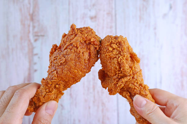 primo piano mano dell'uomo e mano della donna lampeggiante croccante fritto bacchette di pollo contro muro di legno - pollo fritto foto e immagini stock