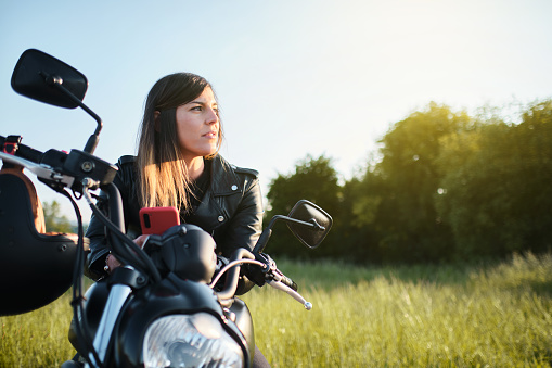 woman sitting on a motorcycle in the countryside at sunset