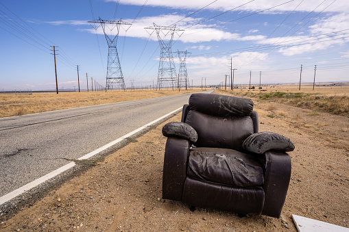 Abandon Recliner Chair Furniture on Desert Road with Power Lines in Dirt