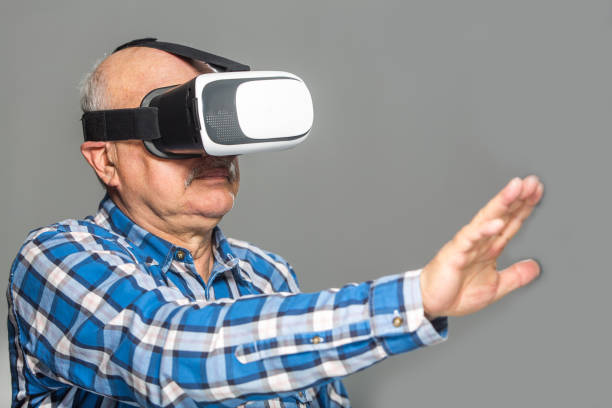 istock Old man in virtual reality glasses over grey background 1318584531