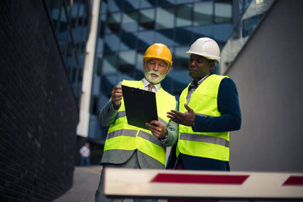 istock Business conversation in progress. Mature engineer discussing the structure of the building with architects colleague at construction site. 1318584900