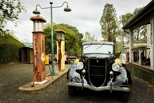 Gatton, Queensland, Australia - October 24, 2020: Front view of a black Ford 1935 Series Street Rod Utility parked next to an old Texaco fuel pump at a garage.