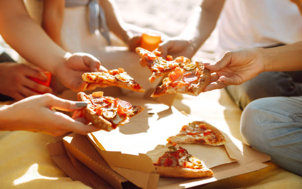 istock Hands taking slices of pizza close view. 1318588027