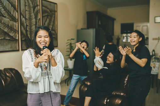 familia asiática cantando karaoke riendo y disfrutando de todos juntos en la sala de estar de su casa photo