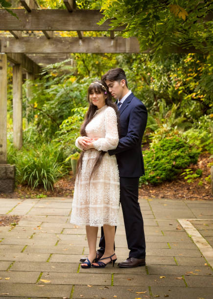 istock Groom in navy suit hugging bride outdoors under vines 1318594314