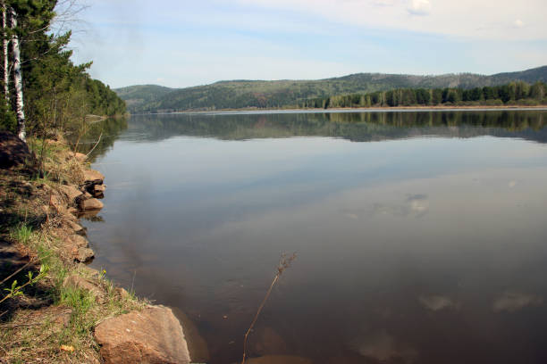 istock View on a calm water surface of the wild river runs between wooded mountains 1318595138