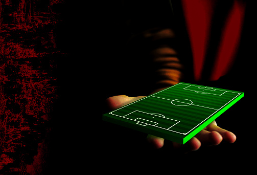 Collage with a human hand holding a green football  pitch. Dark design. It can be used for a website, presentation, soccer game poster,  banner and more