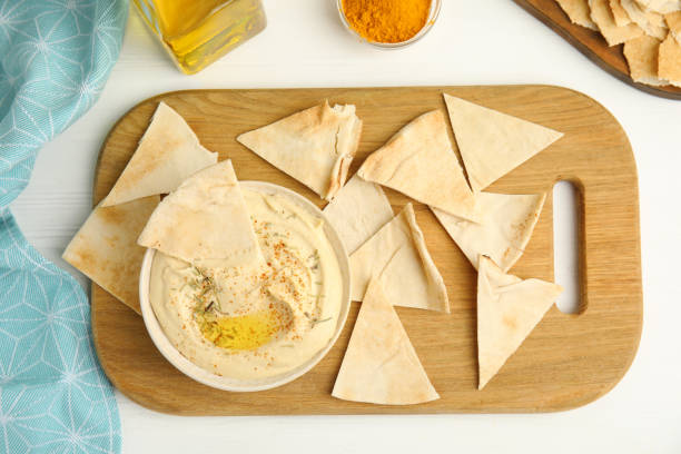 istock Delicious hummus with pita chips on white wooden table, flat lay 1318595839