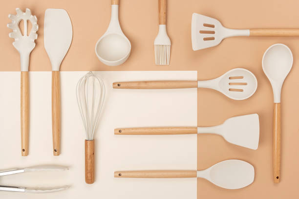 istock Pattern made from cooking utensil set. Silicone kitchen tools with wooden handle on beige background. Top view Flat lay 1318596716