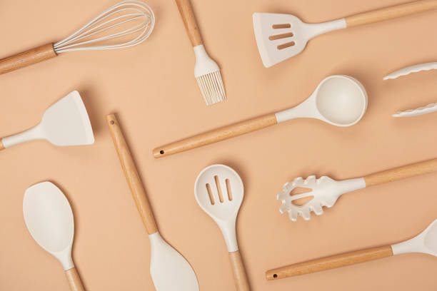 istock Pattern made from cooking utensil set. Silicone kitchen tools with wooden handle on beige background. Top view Flat lay 1318596743