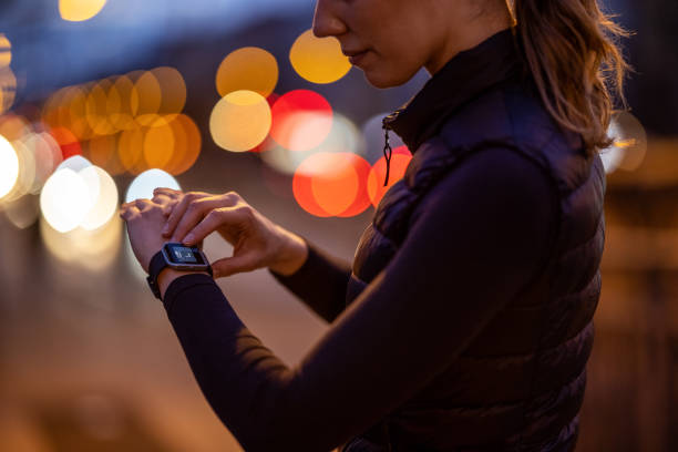 Woman using fitness app on her smartwatch Cropped shot of a woman monitoring fitness process on smartwatch after a workout at night. Woman using a fitness app on her smartwatch. She is outdoors in the city at night for a run. stopwatch photos stock pictures, royalty-free photos & images