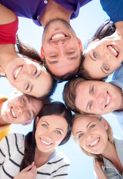 istock smiling friends in circle on summer beach 1318599256