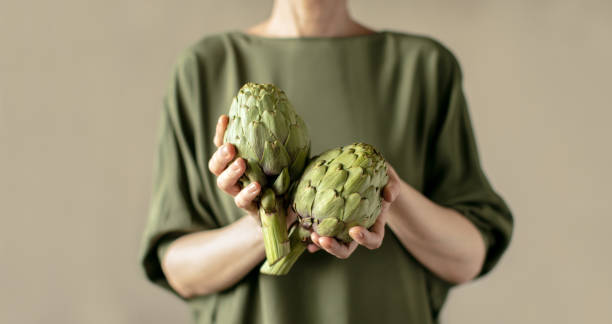 Woman holding fresh ripe artichokes in her hands Woman holding fresh ripe artichokes in her hands, healthy vegetarian food ingredient concept artichoke diet stock pictures, royalty-free photos & images