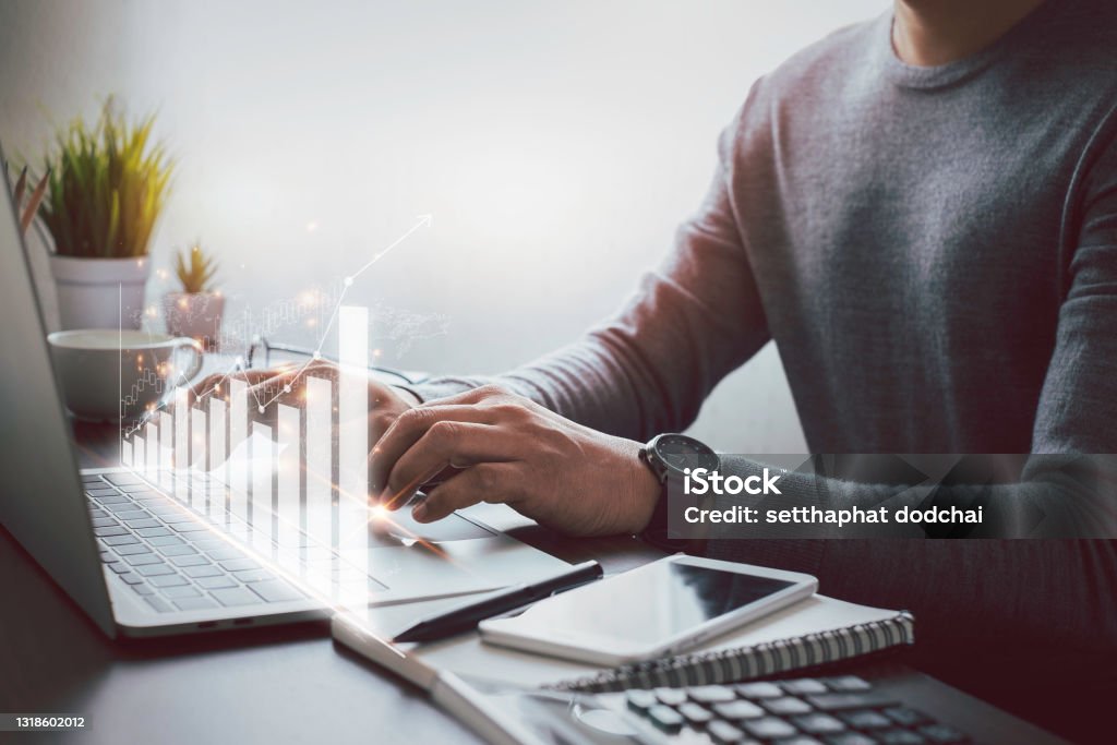 Businessman, hand using and typing keyboard of laptop computer analyzing sales data and economic growth plan graph chart success. Business finance and marketing digital technology concept. Revenue Stock Photo