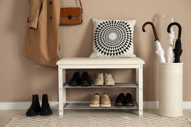 banc élégant de stockage avec différentes paires de chaussures près du mur beige dans le hall - chaussures photos et images de collection