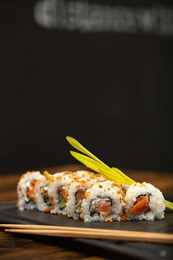 Sushi roll on a white background with Philadelphia cheese and salmon breaded with dried tuna.