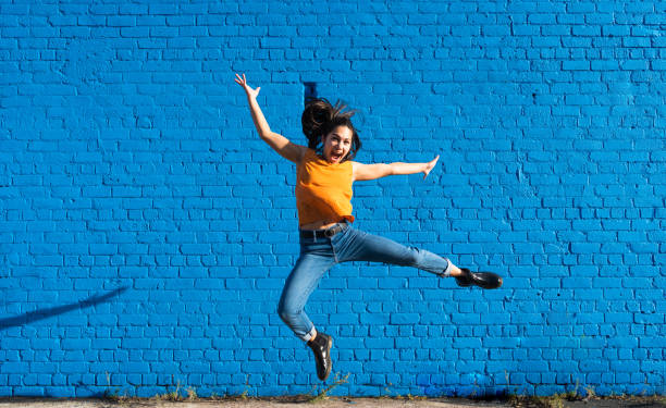 istock woman jumping with smile with blue background. 1318604853