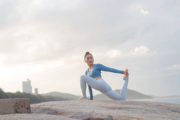 Young attractive Asian woman practicing yoga on the beach.