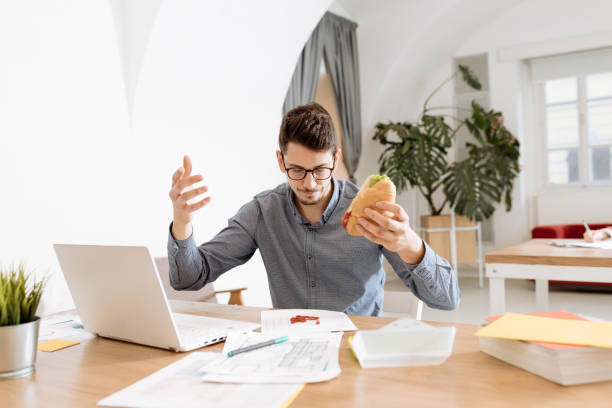 istock Employee eating sandwich and spilling ketchup on documents 1318605449