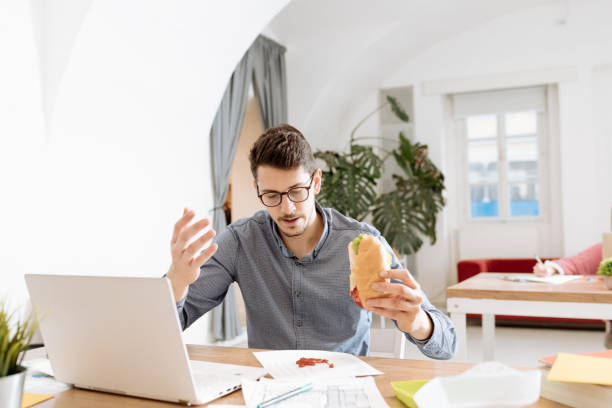 istock Employee eating sandwich and spilling ketchup on documents 1318605669