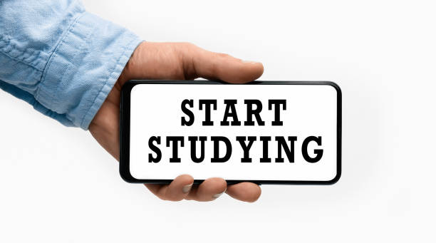 istock Closeup of a male hand holding Smartphone with horizontal text Start Studying on display 1318605697