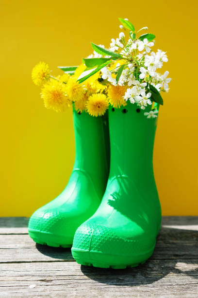 istock Rubber boots with flowers on yellow background 1318607302