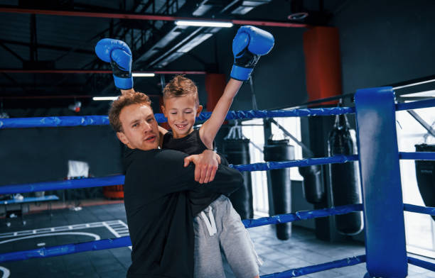 istock Boxing coach standing in the ring with boy and celebrating victory together 1318609732