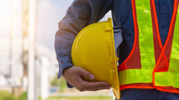 tecnico in possesso di hard hat giallo sicurezza hard hat luce solare sfondo - attrezzatura di sicurezza foto e immagini stock