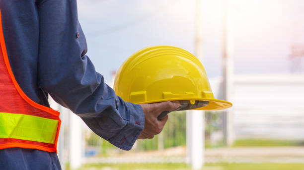 istock Technician holding Yellow hard hat safety hard hat sunlight background 1318611170