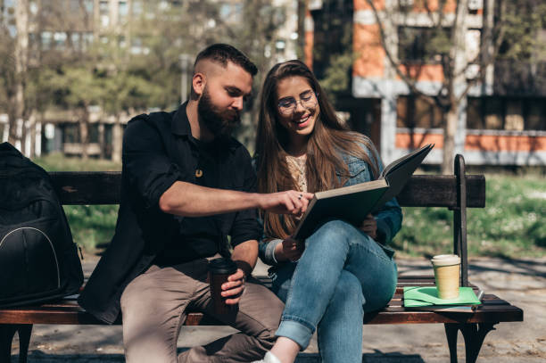 istock Two students sitting on a bench in a campus and studying for their exam 1318613465