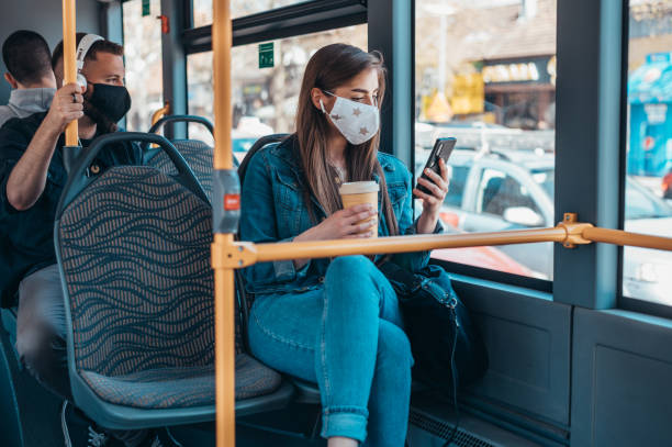 스마트폰을 사용하는 동안 버스를 타고 보호 마스크를 쓴 여성 - pollution mask audio 뉴스 사진 이미지
