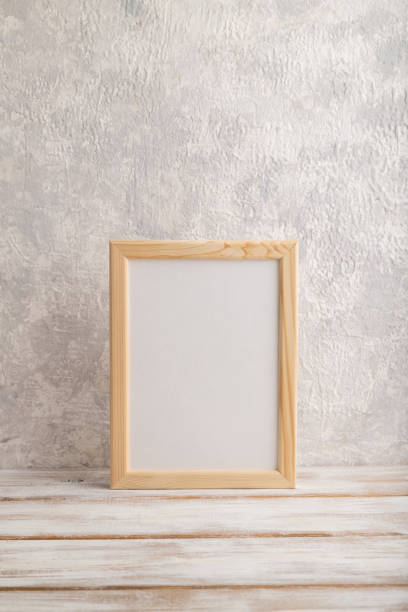 istock White wooden frame mockup on gray concrete background. Blank, vertical orientation, still life, copy space. 1318613663