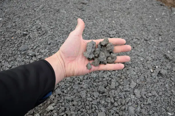 recycled asphalt crumb is used on the edge of the new cycle path and in the subsoil of the asphalt road. between the field and the path behind the curb a parking lot.