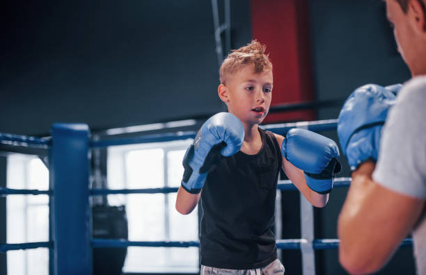 istock Boy in protective gloves have sparring with trainer on the boxing ring 1318614885