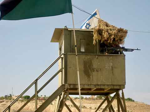 Horizontal photo of an Israeli soldier holding a rifle at a checkpoint tower post between Palestinian territory and Israeli territory near Bethlehem