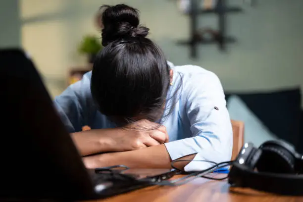 Photo of young Business woman sleeping by closing laptop while working, concept of new normal burnout, over or late night work at home during coronavirus covid-19 pandemic