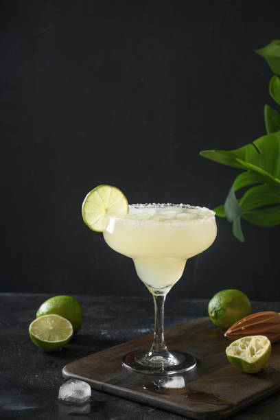istock Classic Margarita cocktail with lime juice and ice cube on black background. Vertical orientation. 1318616339