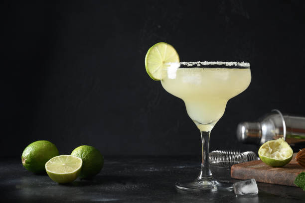 istock Classic Margarita cocktail with lime juice and ice cube on dark black background with copy space. 1318616340