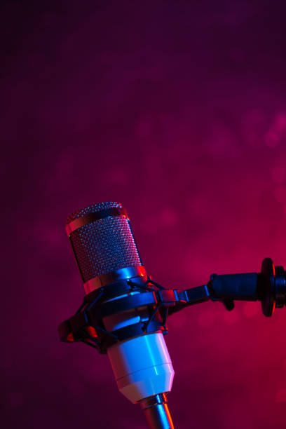 istock Studio condenser microphone on the stand, lots of copy space, color backlight. The concept of sound recording, podcast 1318620264