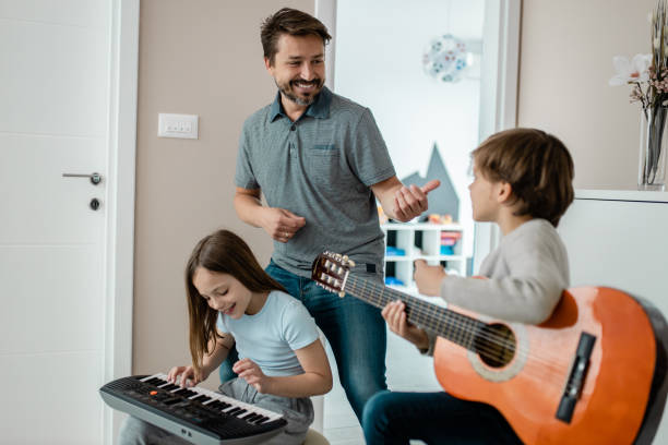 Having fun with father Father and son playing music at home father and son guitar stock pictures, royalty-free photos & images