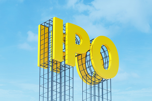 Large yellow signboard on metal frame with the word IPO. Clear sky in the background. Concept of share trading on stock market, capital investment, currency exchange